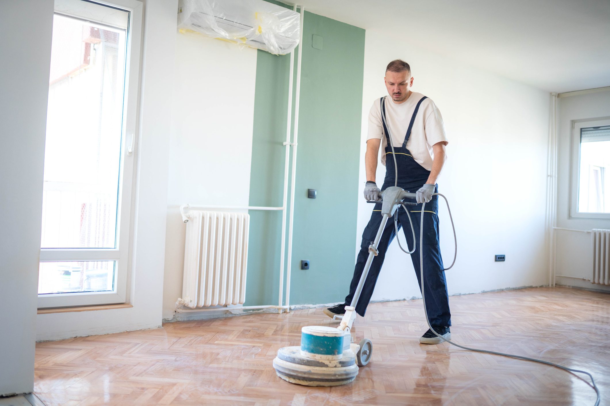 A professional master cleans the floor (parquet) with a polishing machine